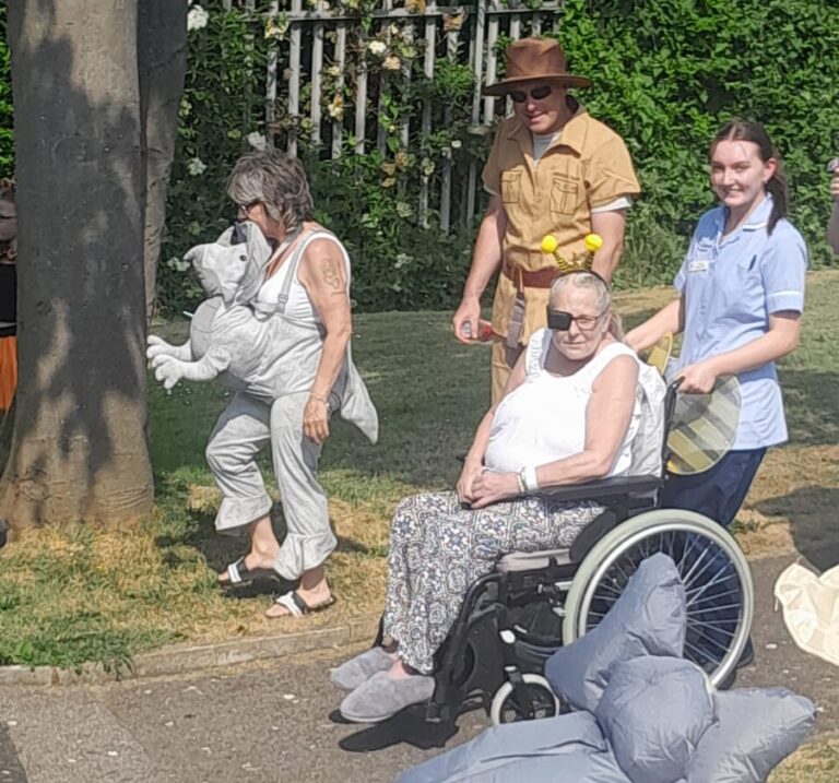 Pauline is pushed around the Rotherham Hospice gardens by a young healthcare support worker, to see her family dressed up as different zoo animals