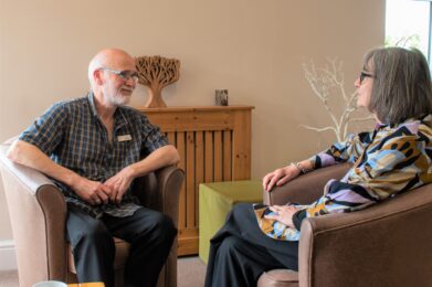 male bereavement counsellor sitting with a woman, listening to her