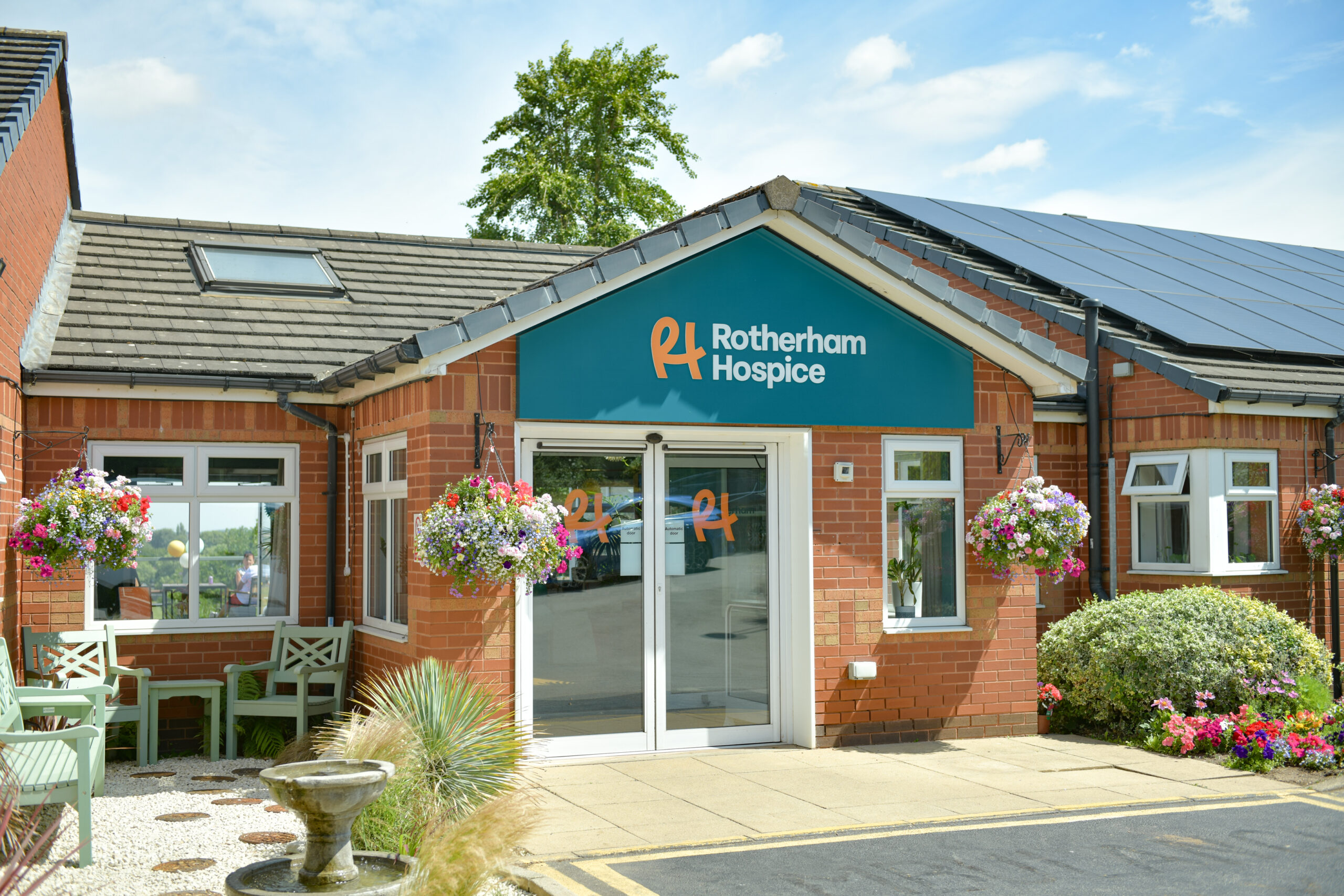 Front entrance of Rotherham Hospice, a local South Yorkshire charity providing outstanding end of life care, with landscaped gardens and welcoming seating area.