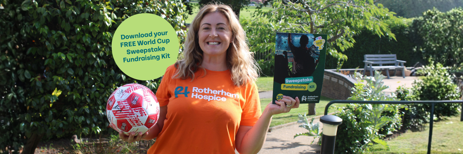A Rotherham Hospice fundraiser in an orange Rotherham Hospice t-shirt holds a signed football and the World Cup Sweepstake Fundraising Kit in the hospice gardens.