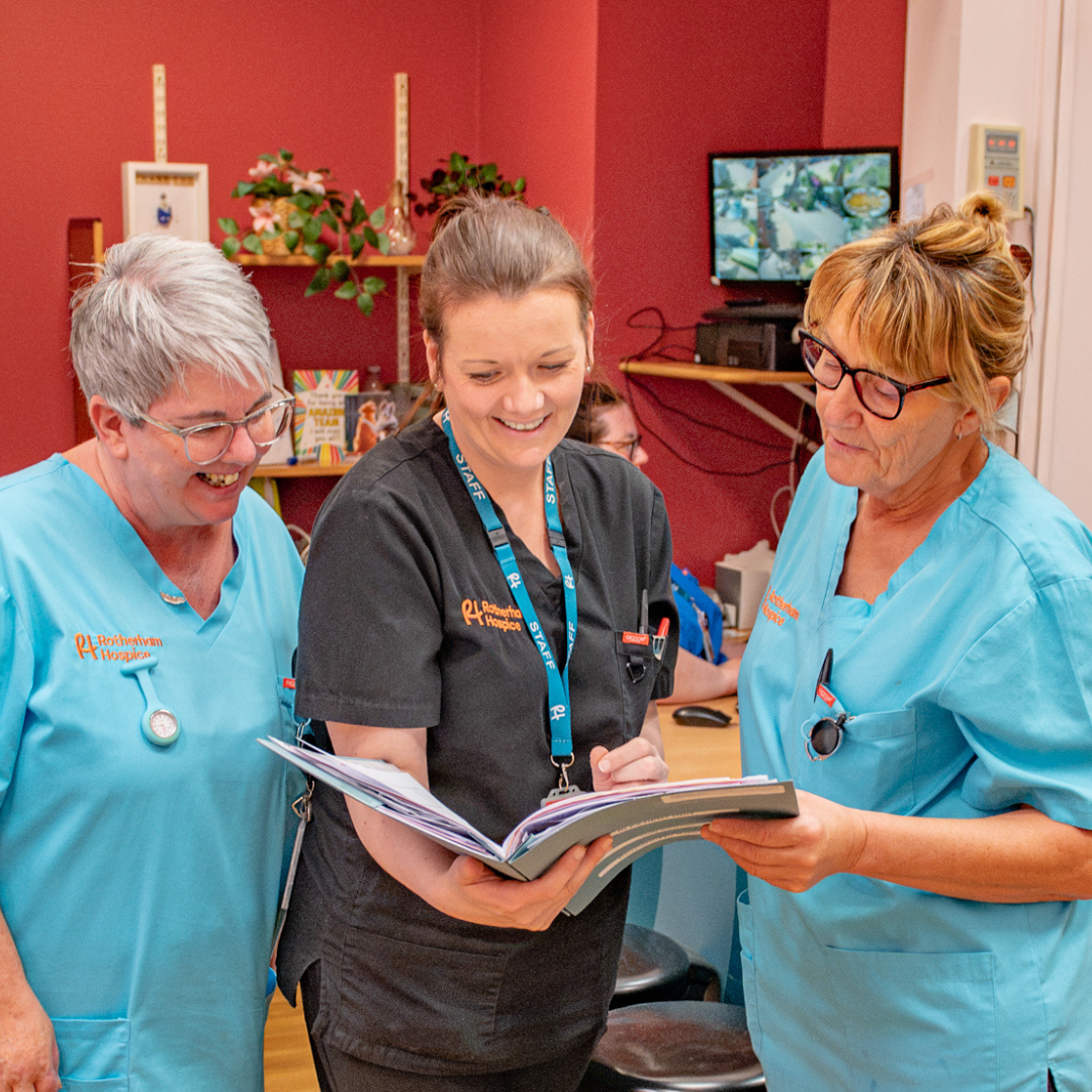Three Rotherham Hospice nurses smiling as they review patient notes together